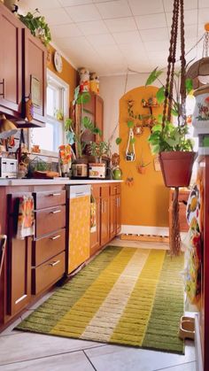 a kitchen with wooden cabinets and green rugs on the floor in front of an orange wall