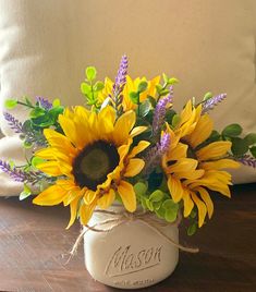 a bouquet of sunflowers and lavender in a mason jar on a wooden table