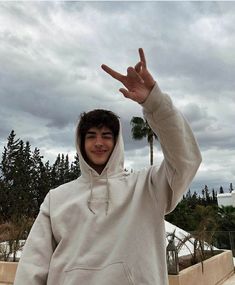 a young man in a white hoodie is making the peace sign with his hand