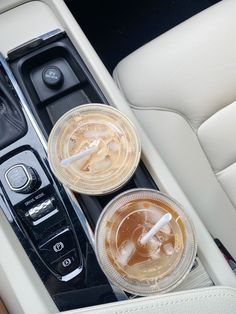 two drinks in plastic cups sitting on the center console of a car