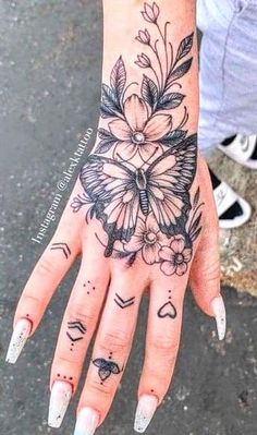 a woman's hand with tattoos on it and flowers in the middle of her left hand