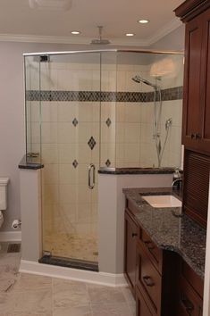 a bathroom with a walk in shower sitting next to a sink and toilet on top of a counter