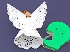 an origami angel with a green toothbrush in it's mouth next to a hole in the paper