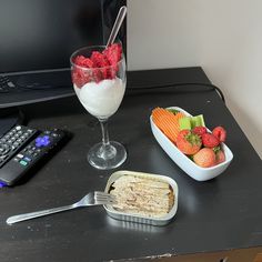 a bowl of strawberries, carrots and crackers next to a glass of milk