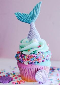 a cupcake decorated with sprinkles and a mermaid tail