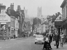 an old black and white photo of people walking down the street