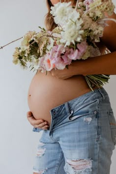 a pregnant woman with flowers in her belly and jeans on the bottom half of her stomach