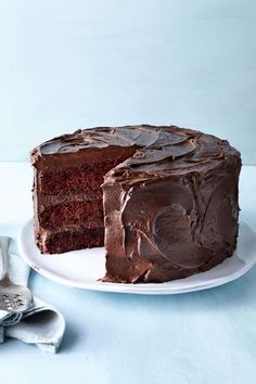 a chocolate cake on a white plate with one slice missing