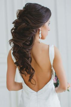 the back of a bride's dress with her hair in half - up style