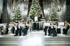 a man standing on top of a stage with musical instruments in front of christmas trees