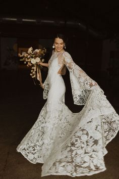 a woman in a wedding dress holding a bouquet and posing for the camera at night