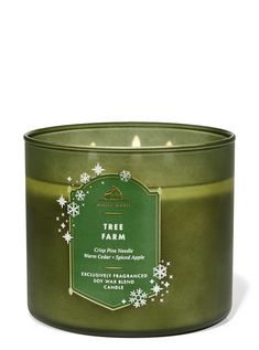 a green candle with white snowflakes on the top and an evergreen tree farm label