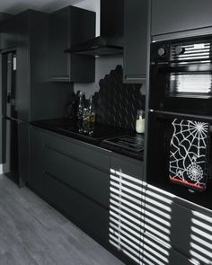 a black and white kitchen with spider web decorations on the stove top, oven hoods and cabinets