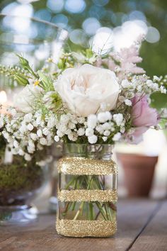 a vase filled with flowers sitting on top of a wooden table next to a candle