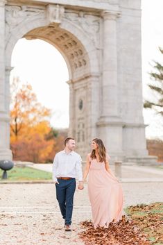 an engaged couple walking in front of the arch of triumph during their fall engagement session