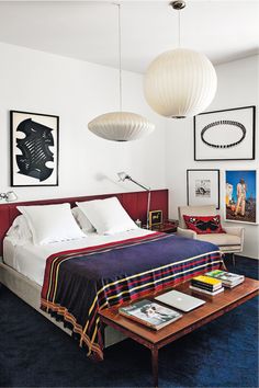 a bed sitting in a bedroom next to a table and lamps on the wall above it