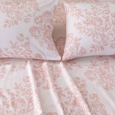 a bed with pink and white sheets and pillows on top of eachother's headboard