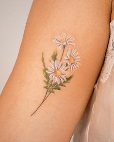 a woman's arm with daisies painted on the back of her arm,