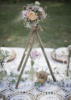 a table topped with flowers and candles on top of a doily covered table cloth