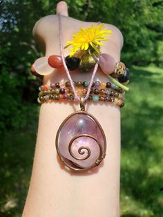 Beautiful spiral wire wrapped tumbled amethyst crystal necklace. Wrapped in bare copper oxidized wire. Comes with a dust pink hemp cord and copper plated steel chain. Often viewed as a stone of peace, some believe amethyst's calming presence produces soothing dreams by bringing the dreamer more in tune with the Divine. This clarity and peacefulness also extends to the waking mind. Amethysts are said to help the mind flow freely in both mental and metaphysical dimensions. Bohemian Wire Wrapped Amethyst Necklace, Adjustable Copper Crystal Necklace With Natural Stones, Bohemian Copper Wire Wrapped Crystal Necklaces, Bohemian Rose Quartz Wire Wrapped Jewelry, Purple Wire Wrapped Copper Wire Necklace, Wire Wrapped Amethyst Necklaces For Meditation, Spiritual Wire-wrapped Rose Quartz Necklace, Amethyst Wire Wrapped Necklace For Meditation, Copper Wire Wrapped Crystal Necklace For Healing