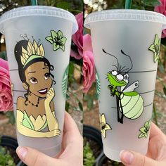 two plastic cups with cartoon characters on them and pink roses in the background, one is holding a straw