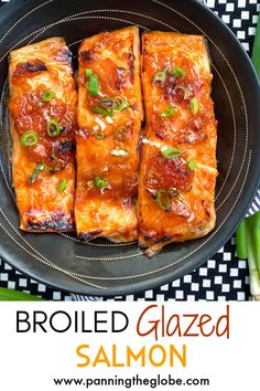 broiled glazed salmon on a black plate with green onions and scallions in the background