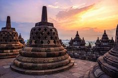 the sun is setting behind some very large stuurs at borobudurg temple in indonesia