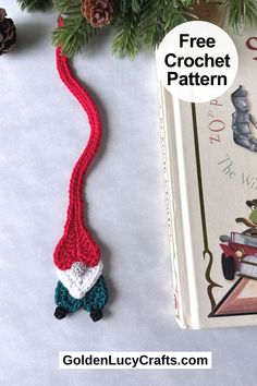 a crocheted bookmark with a red string attached to it next to pine cones