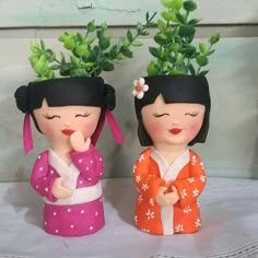 two little figurines are standing next to each other with plants in their heads