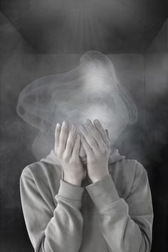 a woman covering her face with both hands while standing in front of a black and white background