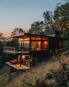 a small house sitting on top of a hill next to trees and bushes at sunset