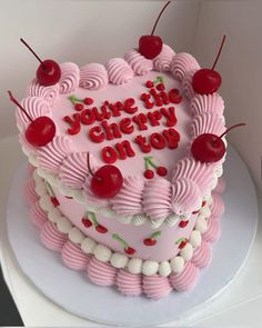 a heart - shaped cake with cherries and the words you're the cherry on top