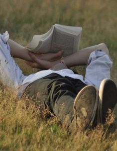 a person laying in the grass reading a book