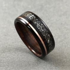 a wooden ring with black and white flowers inlayed to the inside, on a gray surface