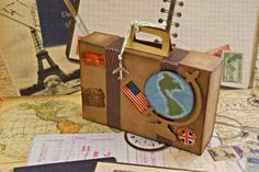 an open suitcase sitting on top of a table covered in maps and other items from around the world