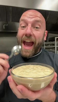 a man holding a bowl of food with a spoon in his hand and looking at the camera