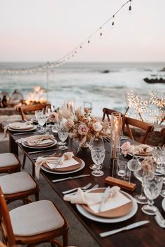 a table set with place settings for dinner by the ocean