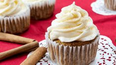 cupcakes with white frosting and cinnamon sticks on a red tablecloth,