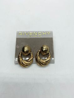 "The ultimate in 80's glam, this dazzling set of Givenchy clip-on earrings is sure to add the WOW factor to your little black dress. These clip-on earrings are a small oval with a semi open tear drop shape hanging freely from the oval, giving lots of movement and golden glow with each toss of your head.  They are carved in a soft, swirling pattern that further enhances their glimmer and shine.  Each earring is marked \"Givenchy\" on the hanging section and \"Givenchy New York - Paris\" on the cl Givenchy Paris, Golden Glow, New Paris, Original Card, Small Photos, Swirl Pattern, Display Cards, Wow Products, Tear Drop