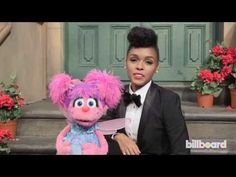 a boy in a tuxedo poses with a pink stuffed animal on the steps