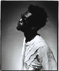 a black and white photo of a man with dreadlocks on his head, looking to the side