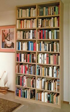 a bookshelf filled with lots of books next to a painting on the wall