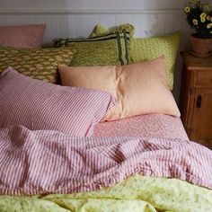 an unmade bed with pink and green sheets