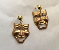 "A fabulous pair of handmade Happy and Sad Faces earrings Theatre Masks Comedy and Tragedy gold tone in raw brass Alternatively you could have both happy or both sad - just ask Please note the masks with stud fittings are smaller than those of the same style with lever back fittings Simple, charming dangle earrings for pierced ears with nickel free stud fittings These lovely face earrings are an unusual pair of statement earrings The detail on the faces are fabulous and have a traditional mask style design  Raw brass has the colour of 9ct gold without the price tag and they can be polished with good quality brass polish See also other earrings in mask / faces style  in silver tone, faces / masks in gold tone.  All finishes are available in happy and sad versions. There are some identical d Nickel-free Novelty Gold Earrings, Novelty Gold Nickel-free Earrings, Nickel-free Gold Novelty Earrings, Gold Novelty Pierced Earrings, Faces Earrings, Traditional Mask, Tragedy Mask, Theatre Masks, Mask Style