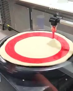 a pizza being made in a kitchen with a red and white circle on the top