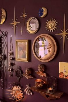 a purple wall with many different types of clocks on it and pictures hanging on the wall