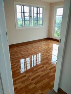 an empty room with hard wood floors and windows