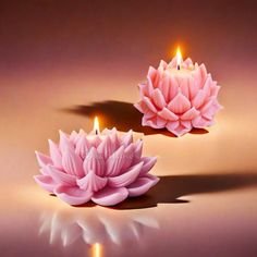 two candles with pink flowers on them sitting next to each other