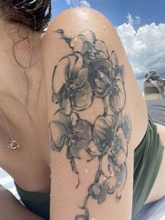 a woman laying on the beach with her arm covered in flowers and watercolors