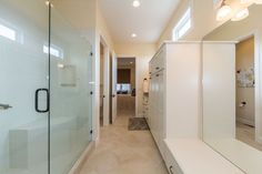 a bathroom with a walk in shower next to a white sink and counter top under two lights